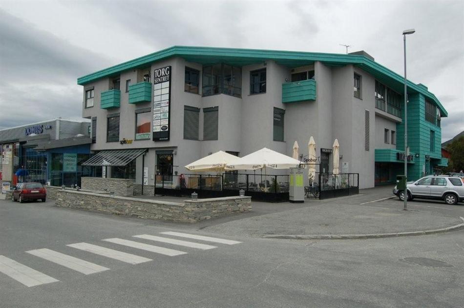 A three-storey corner building with teal details and an outdoor café